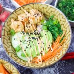 This delicious spicy shrimp poke bowl recipe is served with hot sushi rice, spicy mayo, avocados, radishes, and carrots. A quick weeknight dinner idea