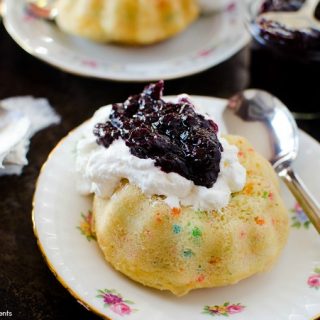 These moist Mini Bundt Cakes are made with confetti sprinkles and served with whipped cream and homemade blueberry compote. Perfect as an elegant dessert.
