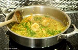 This delicious Curried Riced Cauliflower recipe with shrimp is low carb, paleo and keto friendly. Skillet showing the dish being completed by adding parsley