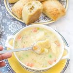 This creamy Potato Dumpling Soup recipe is the perfect hearty vegetarian soup for winter. Enjoy homemade dumplings. Closeup of the soup shown the dumplings and colorful veggies