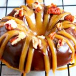 closeup of decadent Baked Turtle Donuts are are glazed with chocolate, sprinkled with toasted pecans and drizzled with sweet caramel. An irresistible dessert that tastes better than the Turtles candy bar