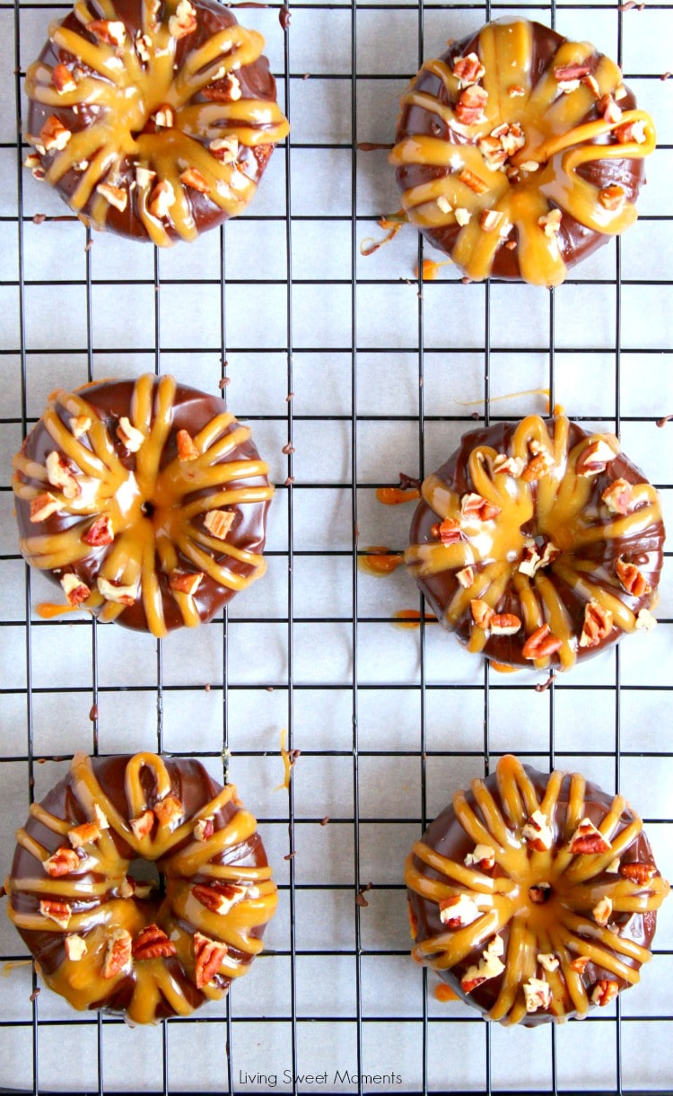 These decadent Baked Turtle Donuts are are glazed with chocolate, sprinkled with toasted pecans and drizzled with sweet caramel. Sheet pan with donuts on top