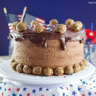 This colossal Peanut Butter Chocolate Cake recipe is made from scratch and is garnished with peanut butter chocolate truffles rolled in peanut butter & cocoa pebbles cereal