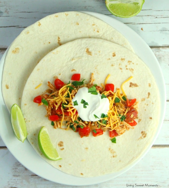 You won't believe how easy these Slow Cooker Shredded Chicken Tacos are to make. Shown a tortilla with the shredded chicken, cheese, and sour cream